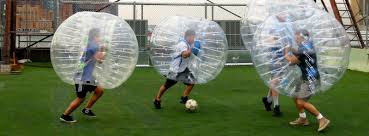 Boys playing soccer inside of battle ball inflatables.